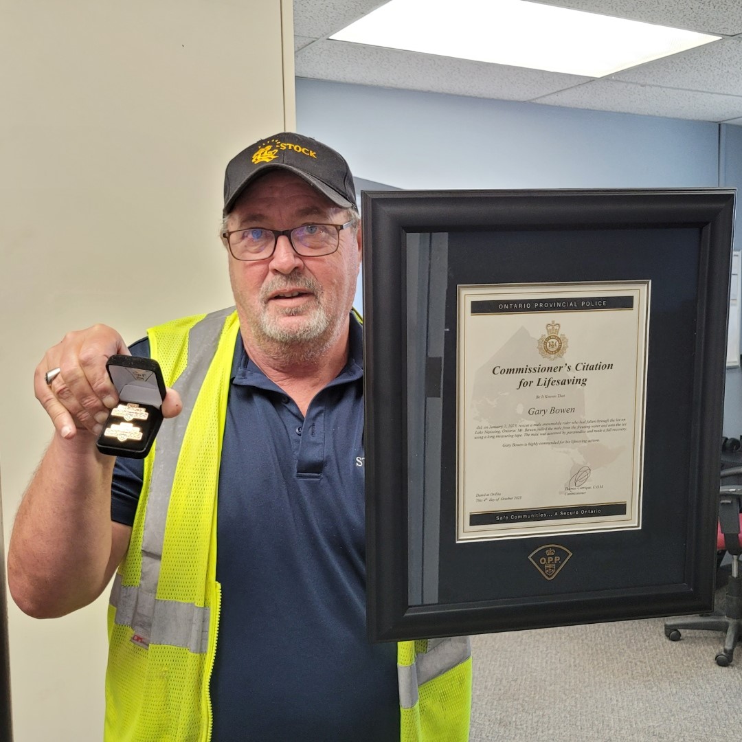 Gary Bowen holding his Commissioner’s Citation for Lifesaving certificate and pin from the Ontario Provincial Police